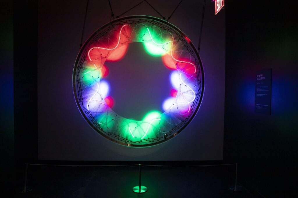 The hand-wired LED ring of light hangs suspended from the ceiling, casting a bright, circular glow on the wall.