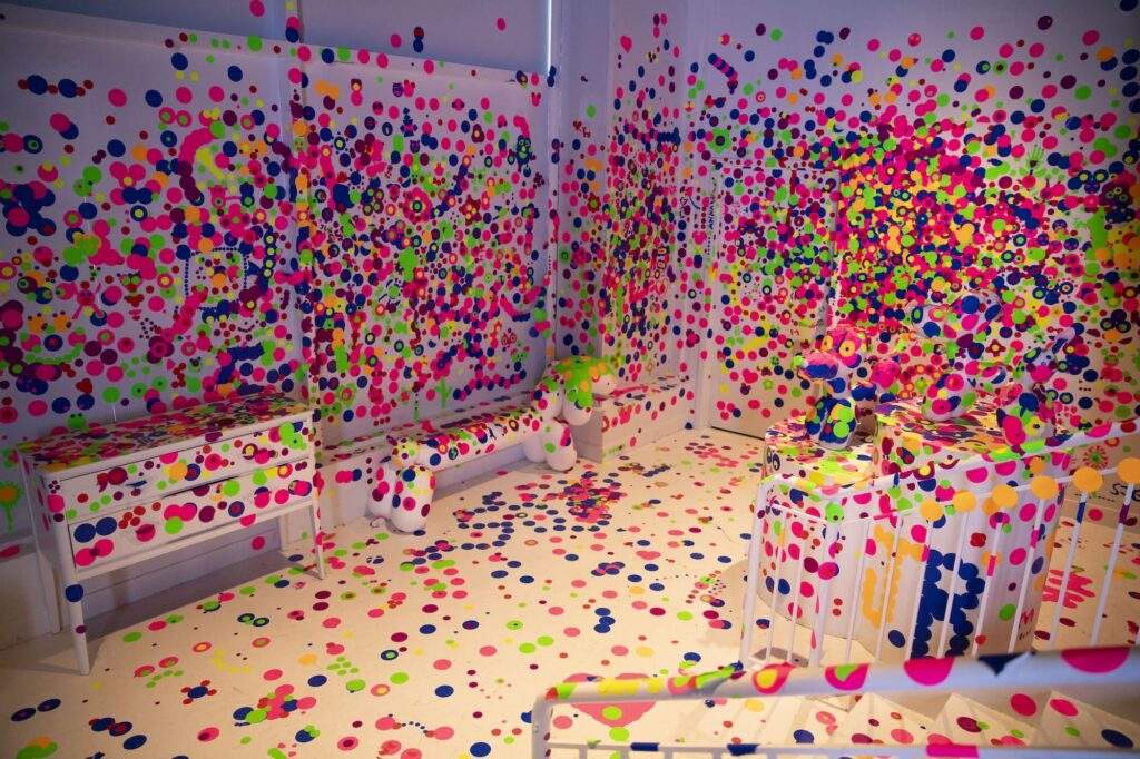 A white room with pink, blue, yellow, and green dot stickers plastered across every surface.